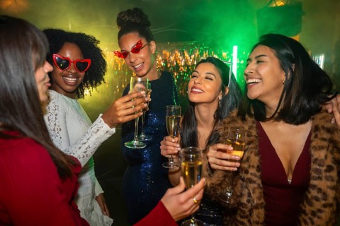 Diverse group of young women friends happily toasting with champagne flutes, celebrating a special