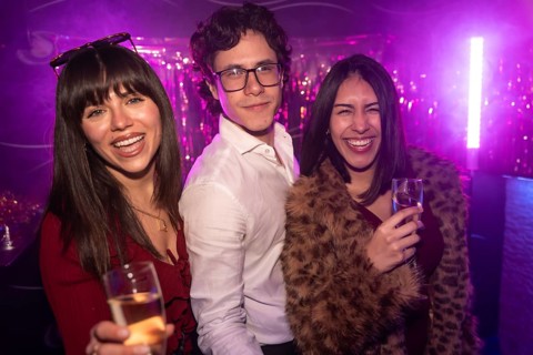 Young friends enjoying a vibrant party atmosphere, smiling and laughing while holding glasses of