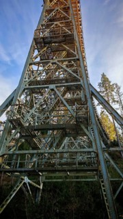 Vertical view of a high metal bridge, old railroad bridge, in front of a bright blue sky,