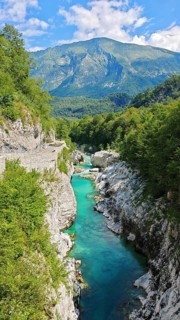 Gorge with clear water and surrounding green mountains under blue sky, Soca Valley, Slovenia