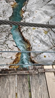 Wooden bridge over turquoise river between bright, rocky banks, Soca Valley, Slovenia