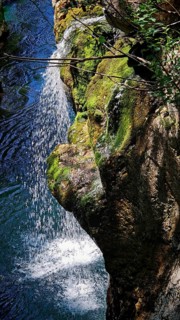 Waterfall runs over moss-covered rocks and splashes into a blue pool, Soca Valley, Slovenia