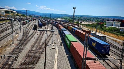 Large freight yard with lots of containers and train tracks under a blue sky, Slovenia