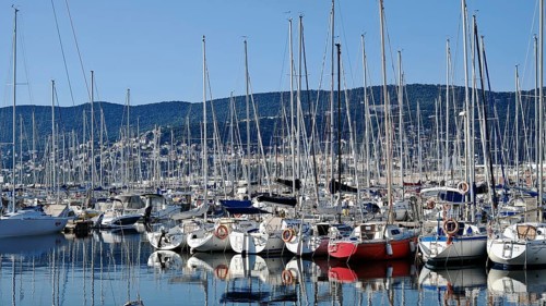 Lots of boats in a marina surrounded by mountains under clear blue skies, Slovenia