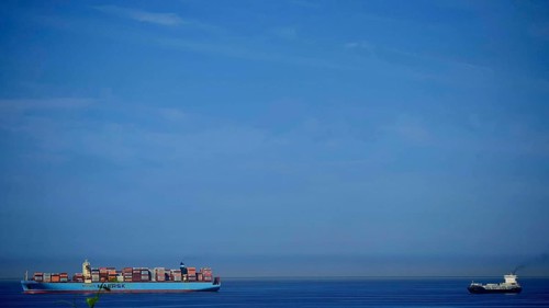 Large cargo ship full of containers on open sea with clear blue sky, Slovenia