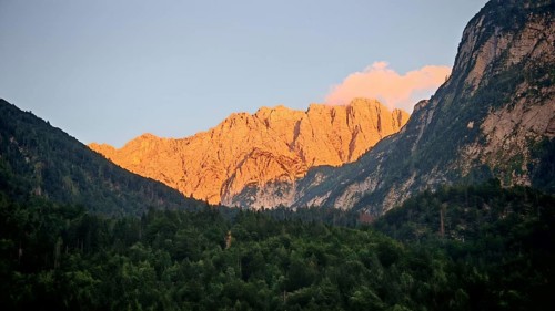 Mountains at sunset with impressively illuminated rocks and dark forest in the foreground, Slovenia