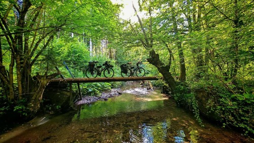 Two bikes on a bridge across a river in a green forest, Slovenia