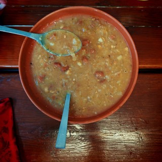 A plate of stew on a wooden table with a spoon lying next to it, Slovenia