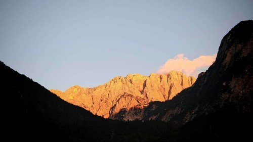 Mountains at sunset with golden light on rocks and dark silhouette of a mountain, Slovenia