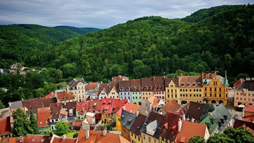 Historic town with colorful roofs surrounded by wooded hills, view of Loket, Czech Republic