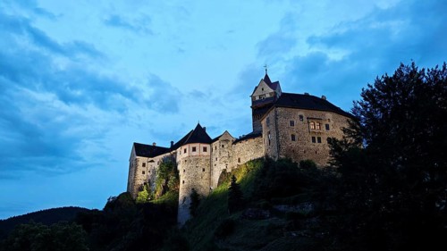 Illuminated castle at dusk against a blue sky, Loket, Czech Republic