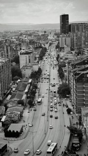 Urban scene with a long busy street lined with tall buildings in black and white, Pristina, Kosovo