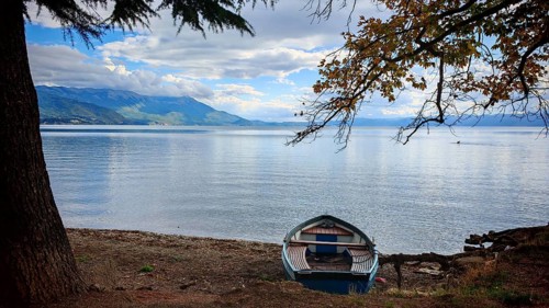 A boat is quietly lying on the shore of a lake with autumn colors, Lake Ohrid, North Macedonia