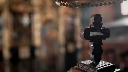 An intricately carved wooden cross against a blurred church background with mystical reflections,