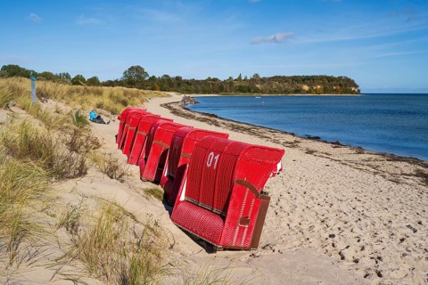 Red beach chairs side by side on sandy beach, beach and cliffs, people on the beach, autumn, Lobbe,