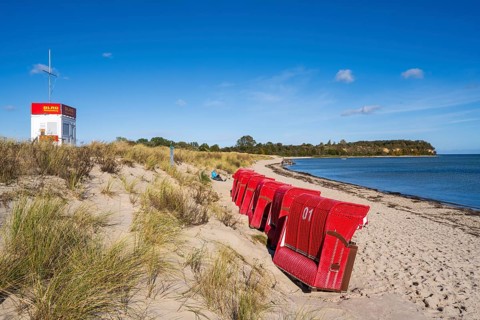 DLRG water rescue, red beach chairs side by side on sandy beach, beach and cliffs, people on the