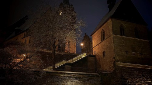 Illuminated church in the dark, surrounded by trees, conveys medieval atmosphere, view of Kronach,