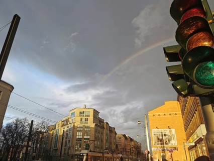 Rainbow over urban scene with traffic light and cloudy sky, Berlin