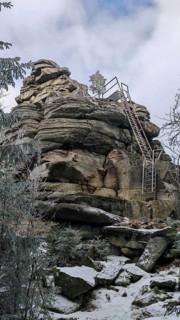 Rock formation with metal stairs in snow surrounded by a wintry sky, Fichtelgebirge