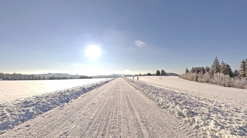 Wide snowy landscape under blue sky with bright sunshine, snowy road, Fichtelgebirge