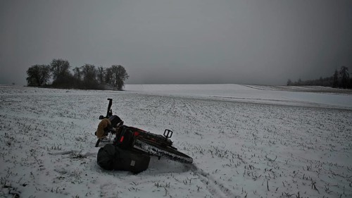 Bicycle lying in the snow on a field with trees in the background under a grey sky, Frankenwald