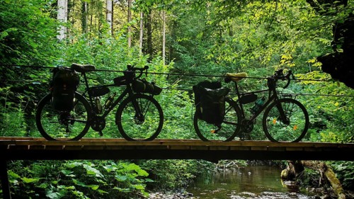 Two bikes on a wooden bridge over a river in the middle of a forest, Slovenia