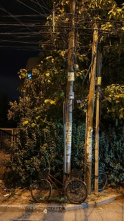 Bicycle leaning against a power pole under a street lamp at night, Montenegro