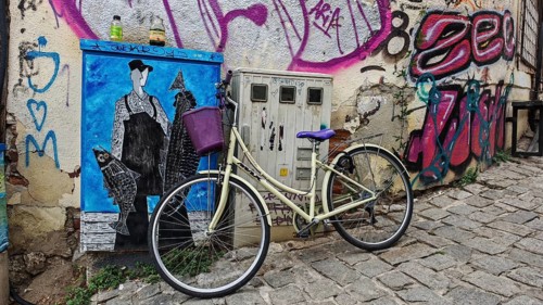 Vintage bicycle leaning against graffiti-decorated wall in urban setting, creative and lively