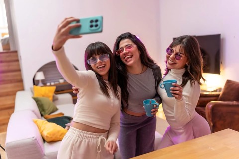 Group of happy young women friends wearing stylish sunglasses and holding drinks, capturing a fun