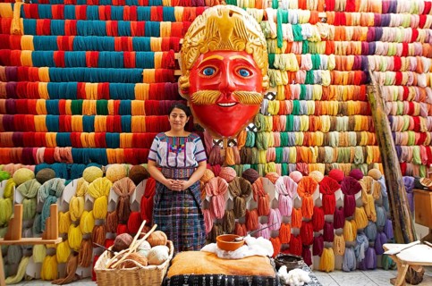 Maya woman, 42 years old, next to a mask of a Moro or Moor for the traditional mask dance, behind a