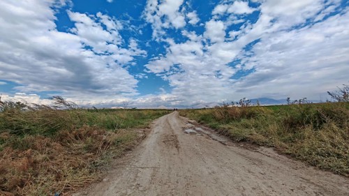 A lonely dirt road leads through a vast landscape under a dramatic cloudy sky, Armenia