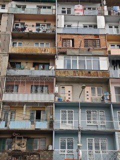 An urban high-rise building with various colorful balconies showing different areas of life,