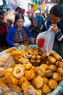 Mayan woman in traditional clothing buys bread at the market in Sololá, Highlands, Sololá