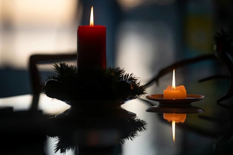 Two candles stand on a table in front of a window at dusk and create a Christmas atmosphere,
