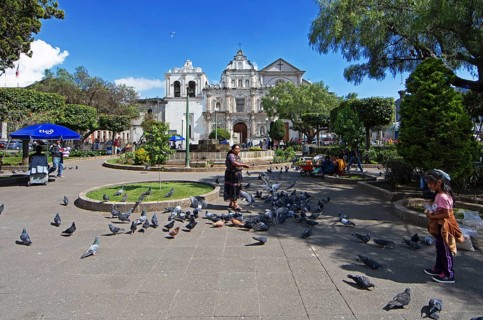 Parque Centroamérica or Parque Central, a Mayan woman in traditional clothing feeds pigeons, in the