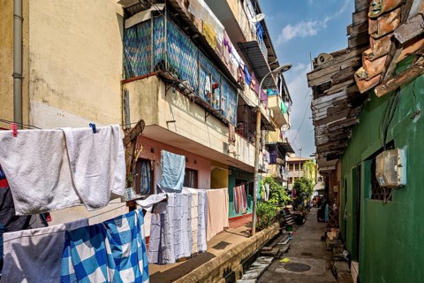 Narrow alley with colorful residential buildings and hanging laundry, lively and traditional