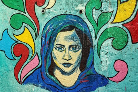Colorful wall mural of a woman with a headscarf on a light blue background