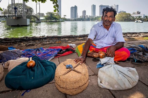 Man on the riverbank with filled baskets against an urban backdrop, relaxed and traditional