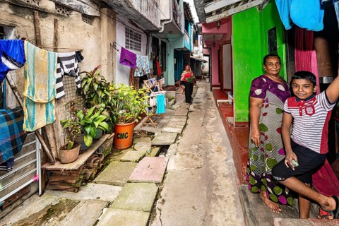 People in front of colorful houses in an alley with laundry hanging in the foreground