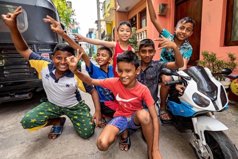 Children pose with a toy motorcycle on the street and are obviously having fun