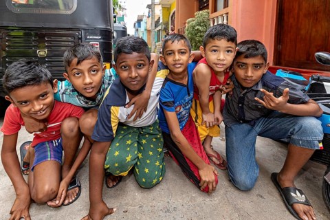 Six children pose happily on the street in colorful clothes, showing joy