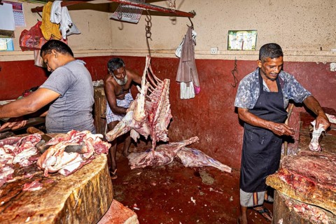 Butcher in a factory processing meat, with various pieces of meat