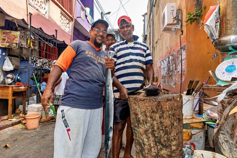 Friendly people pose at a busy street market surrounded by cooking supplies