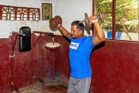 Man weightlifting in a traditional gym, focus on building muscle