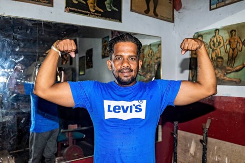 Man proudly shows off his muscle strength in a traditional fitness room