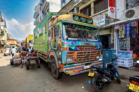 Colourful truck on a busy Indian street with shops and people in sunny weather, The colorful trucks