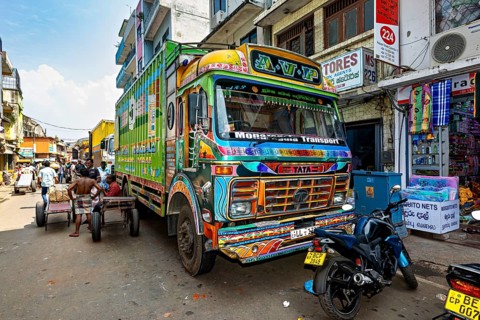 Workers load a truck with large packages on a busy city street, The colorful trucks in the streets
