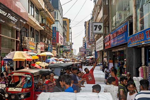 Close-traffic street market with people, rickshaws and colorful shop facades, the hustle and bustle