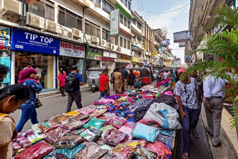 Street market with laid-out clothes and busy foot traffic, the hustle and bustle of Colombo city