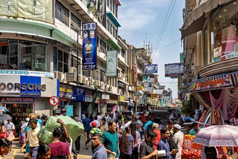 Bustling street scene with lots of people and shops under blue skies, the hustle and bustle of